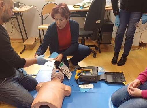 Prowadzący szkolenie wraz z uczestnikiem wykonując ćwiczenia na fantomie do rsyscytacji z wykorzystaniem ćwiczebnego defibrylatora AED.